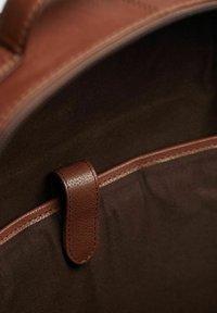 Ruskea nahkainen sisustus laukussa, jossa on sileä pinta, säilytyslokero yhteensopivalla vetoketjulla ja yläreunassa oleva saranat käyttöä helpottamaan.