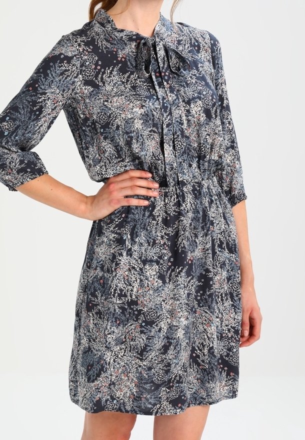 Robe à imprimé floral bleu foncé, avec un col à revers et une taille à cordon. Manches longues avec poignets retroussés, tissu léger.