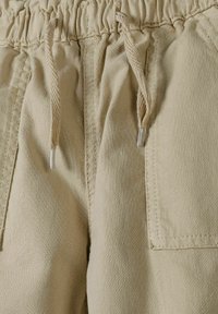 Beige katoenen shorts met een elastische tailleband en trekkoord, voorzien van twee voorzakken en een gladde, gestructureerde stof.
