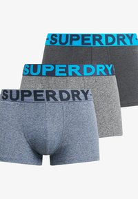 Tres pares de pantalones cortos de hombre en diferentes tonos de azul y gris, cada uno con una banda elástica de marca en azul o marino que contrasta.
