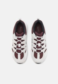 Paire de baskets Nike bordeaux et blanches en tissu mesh, à lacets, avec logos visibles de la marque sur les semelles intérieures, vue de dessus sur fond blanc.