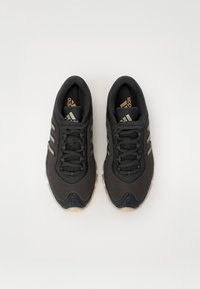 Czarne buty sportowe z siateczkową cholewką, trzema białymi paskami, zaokrąglonym noskiem, teksturowaną podeszwą i czarnymi sznurówkami. Złote logo na języku.