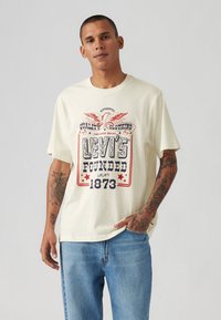 Crème T-shirt met korte mouwen, voorzien van een grote, veelkleurige grafische print met een adelaar, sterren en "Levi's Founded 1873." Standaard pasvorm.