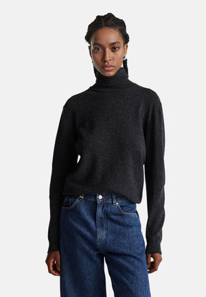 Donkergrijze coltrui met lange mouwen, gemaakt van een zacht, textuurmateriaal; gecombineerd met high-waisted blauwe denim jeans.
