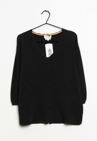 Czarny sweter dzianinowy z dekoltem w serek, rękawami o długości trzech ćwiartek oraz pomarańczowym akcentem wewnątrz dekoltu. Metka z widocznym kodem kreskowym.