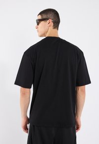 Sort bomulds T-shirt med korte ærmer, en klassisk rund halsudskæring og en afslappet pasform. Den har en glat tekstur og ingen synlige mønstre eller logoer.