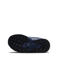 Suela de goma negra de un zapato con un patrón de huella detallado; la parte superior es de color azul claro con acentos oscuros y una textura suave.