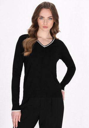 Maglione nero a V con maniche lunghe, caratterizzato da una rifinitura bianca lungo ilcollo e i polsini. Materiale in maglia morbida, silhouette aderente.