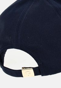 Mørkeblå baseball-cap med en bøjet skygge, lavet af tekstureret stof, med en guldmetal-lukning til justering bagpå.