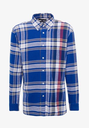 Niebieska koszula w kratę z dużymi kwadratami w odcieniach niebieskiego, szarości i bieli, z czerwonym akcentem; wykonana z miękkiego materiału z kołnierzykiem zapinanym na guziki.