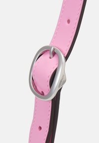 Bracelet en cuir rose avec boucle métallique ovale argentée et bords cousus, présenté en gros plan sur un fond clair uni.