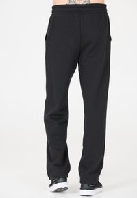Zwarte katoenen sweatpants met een elastische tailleband, zijzakken en een taps toelopende pasvorm. Eenvoudig ontwerp, geen zichtbare patronen of accenten.