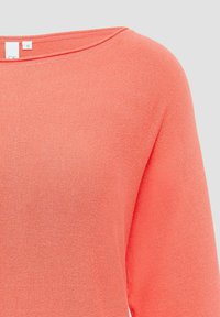 Korallfarbener Stricktop mit weitem Ausschnitt und drei Viertelärmeln. Die Textur ist glatt mit einem gerippten Muster. Größenetikett sichtbar.