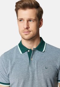 Szary polo z zielonym kołnierzykiem i paskowanymi akcentami, z delikatnym wzorem teksturowym i dwoma guzikami przy szyi.