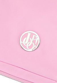 Pochette in tessuto rosa con un logo rotondo in argento e lettering ritagliato. Texture liscia con un dettaglio zip a contrasto in basso.