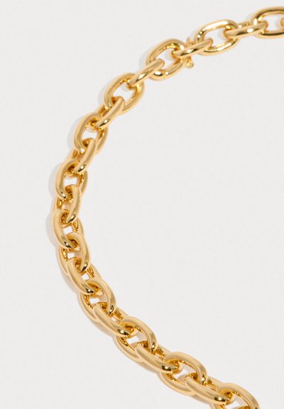 Del nakita iz sijoče zlate verige z ovalnimi članki na svetlem ozadju.