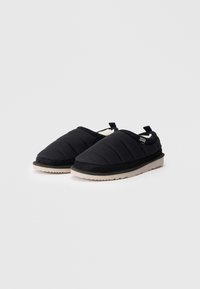 Pantofole nere slip-on con tessuto trapuntato, fodera in pelliccia bianca e suola beige chiaro. Presentano una suola esterna nera testurizzata e una linguetta sul retro.