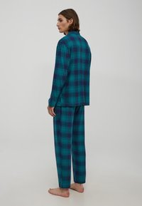 Turkusowy, w kratkę, zestaw piżamowy z długimi rękawami i spodniami. Charakteryzuje się klasycznym wzorem w kratkę z ciemnofioletowymi i niebieskimi akcentami, wykonany z miękkiego materiału.