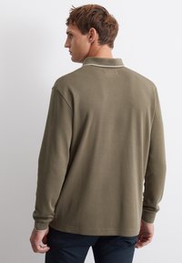 Olivgrünes Langarm-Polohemd mit umgeschlagenem Kragen und kontrastierenden hellen Akzenten. Glatte Textur, lockere Passform und keine sichtbare Markenkennzeichnung.