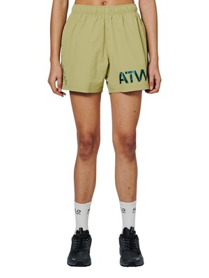 Ben iført lysegrønne elastiske shorts med "ATW" logo på venstre side, hvide strømper med sort tekst og sorte sportssko.