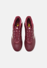 Scarpe da calcio color marrone scuro con una tomaia in pelle elegante, caratterizzate da dettagli bianchi e una suola testurizzata. I lacci passano attraverso sette asole per una vestibilità sicura.