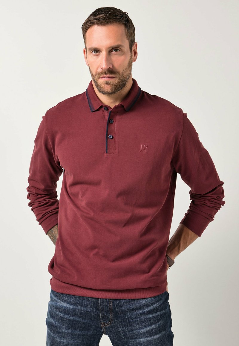 Bordeaux lange mouwen polo met kraag, drie knoopsluitingen en marineblauwe accenten. Voorzien van een geborduurd logo op de borst.