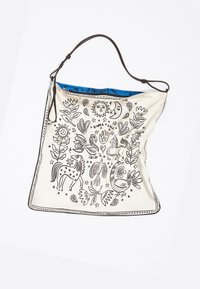 Kremowa torebka z czarnymi wzorami w kształcie zwierząt i kwiatów. Niebieskie wnętrze, regulowany brązowy pasek, miękka tekstura.