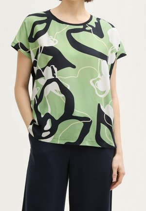 Blusa de manga corta con patrón verde y negro, con cuello redondo y diseños abstractos en blanco y verde claro. Tela suave y ajuste relajado.