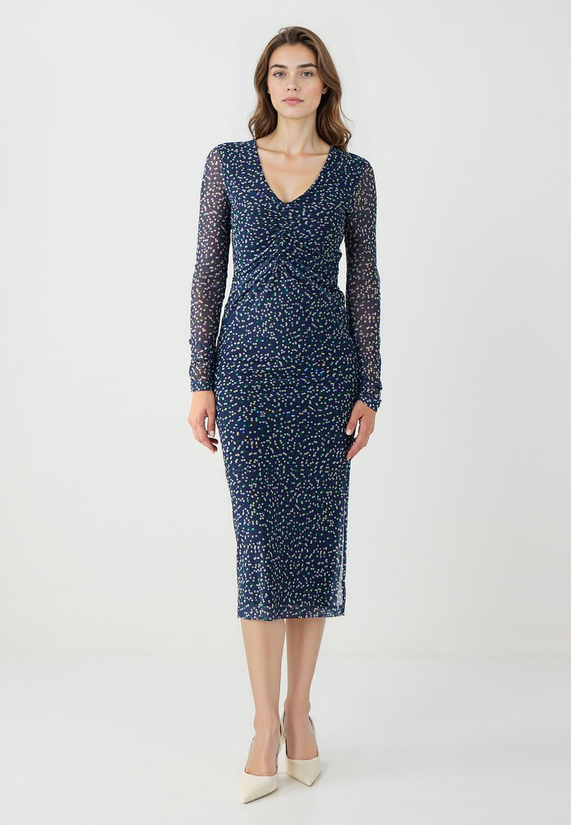 Abito blu navy con maniche lunghe trasparenti, davanti arricciato e motivo a pois multicolore. Design aderente, lunghezza al ginocchio con silhouette dritta.