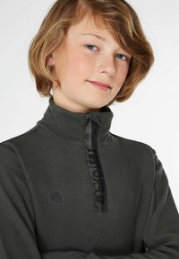 Pull-over en polaire gris foncé avec un col haut, doté d'une fermeture éclair noire d'un quart et d'un détail logo sur la poitrine. Texture douce, design décontracté.