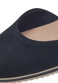 Navy modré semišové slip-on boty s zaobleným otvorem a béžovou stélkou. Mají texturovanou látku a světlou odolnou podrážku.