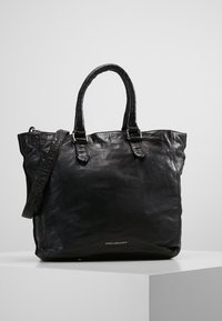 Sac cabas en cuir noir avec deux poignées supérieures, une bandoulière amovible et une texture lisse. Présente un logo en bas.