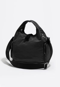 Črna najlon torbica z dvojnima zgornjima ročajema, odklopnim ramenskim trakom, zadrgo na straneh in zatezno zapiranje. Gladka tekstura, minimalističen dizajn.