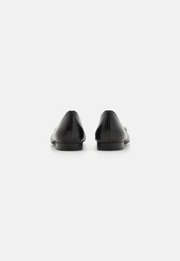 Bailarinas de cuero negro con punta redondeada, tacón bajo y textura suave. Diseño minimalista con una silueta limpia, adecuadas para varios conjuntos.