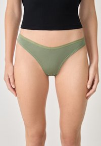 Grüne, gerippte Stringunterwäsche mit einem weichen Gummibund, die ein minimalistisches Design und elastisches Material für zusätzlichen Komfort bietet.