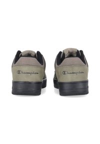 Zapatillas verdes de ante con acentos negros, con un diseño texturizado, cuello acolchado y suela de goma; logo "Champion" en el talón.