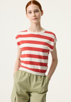 Top de punto de manga corta a rayas rojas y blancas con cuello redondo, combinado con pantalones verde claro de cintura elástica con bolsillos laterales.