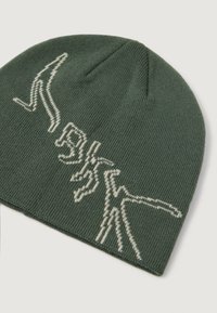 Gorro de punto verde oscuro con patrones de líneas abstractas blancas tejidas en la parte frontal, exhibido sobre un fondo claro.