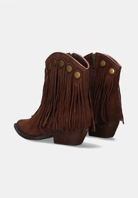 Botas de ante marrón hasta el tobillo con detalles de flecos, punta redondeada y acentos de botón de latón. Cuenta con un tacón bajo apilado y cierre de cremallera lateral.