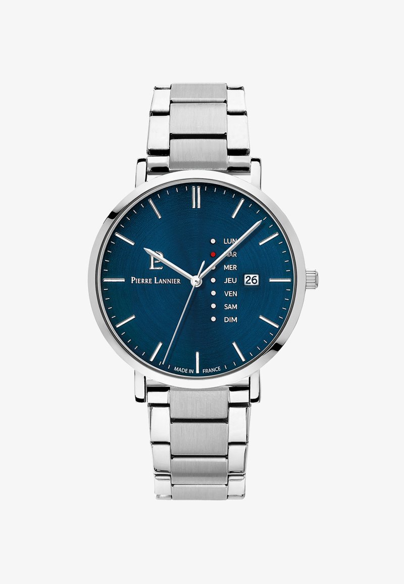 Sudraba nerūsējošā tērauda pulkstenis ar zilu ciparnīcu, sudraba stundu marķieriem, datuma rādītāju un nedēļas dienu indikatoriem katrai nedēļas dienai. Apaļš dizains.