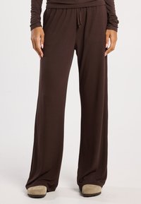 Ruskeat, leveälahkeiset housut, joissa on joustava vyötärö ja naru. Valmistettu pehmeästä, ryppyisestä kankaasta, jossa on väljä istuvuus mukavuutta varten.