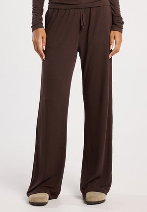 Bruine, wijde broek met een elastische tailleband en trekkoord. Gemaakt van zachte, geribbelde stof en heeft een losse pasvorm voor comfort.