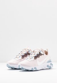 Nike React-sneakers i ljusrosa och vitt med en strukturerad mörkbrun accent, med blå snören och design av bubbel-sula.