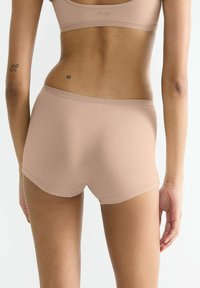 Beige seamless shorts made of soft fabric, featuring a mid-rise waist and smooth edges for comfort. Minimal branding on the waistband.