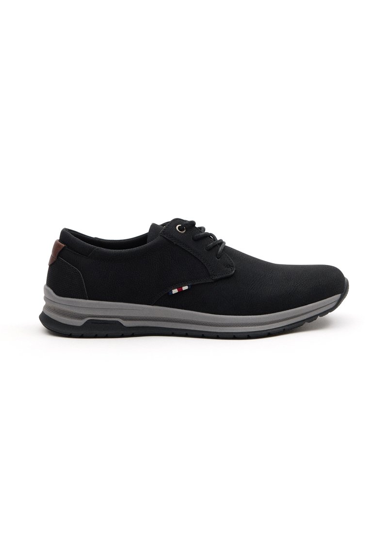 Zapatos casuales negros con una parte superior texturizada, suela de goma gris y acento marrón en el talón; cuentan con un diseño de cordones y detalles de color sutiles.