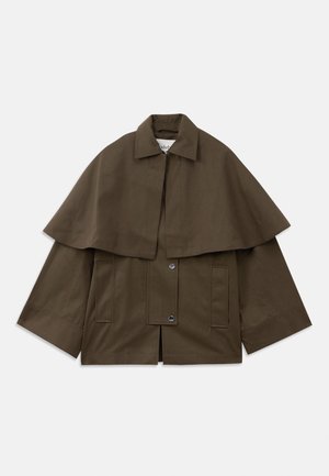 Veste marron, de forme carrée, avec un col et un superposé semblable à une cape. Elle possède deux poches à l'avant et des fermetures à pression pour le maintien. Matériau en coton structuré.