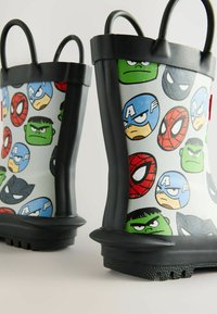 Bottes de pluie en caoutchouc noir ornées d'un motif coloré de personnages de dessin animé, incluant des visages issus de thèmes de super-héros populaires, avec deux poignées.
