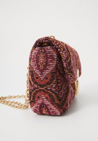 Kangast käekott punase, oranži ja musta kudumise mustriga; omab kuldset ahelat ja volditud ülaosa disaini.