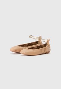 Nudefargede lærballerinasko med elastisk topp, avrundet tå og gullspenne rundt ankelen. Flate såler med minimal mønster.