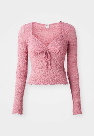 Roza, teksturirana dolga majica z dolgimi rokavi in V-izrezom, z detajlom za zavezovanje spredaj in nabranim dizajnom tkanine. Lahka in oprijeta.